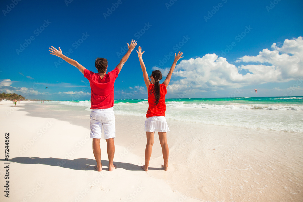 Back view of young couple spread their arms standing on white Back view of young couple spread their arms standing on white
