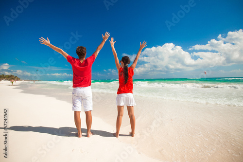 Back view of young couple spread their arms standing on white