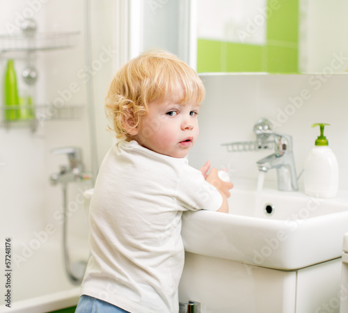kid washing hands with soap in bathroom