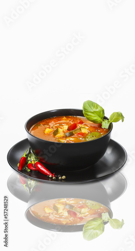 Tomato soup decorated with basil leaf on white background. Copy