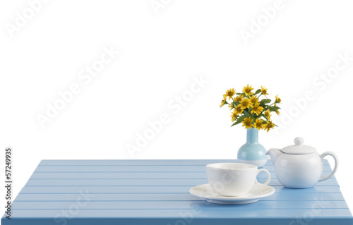 A porcelain cup and teapot on the wooden table with empty space