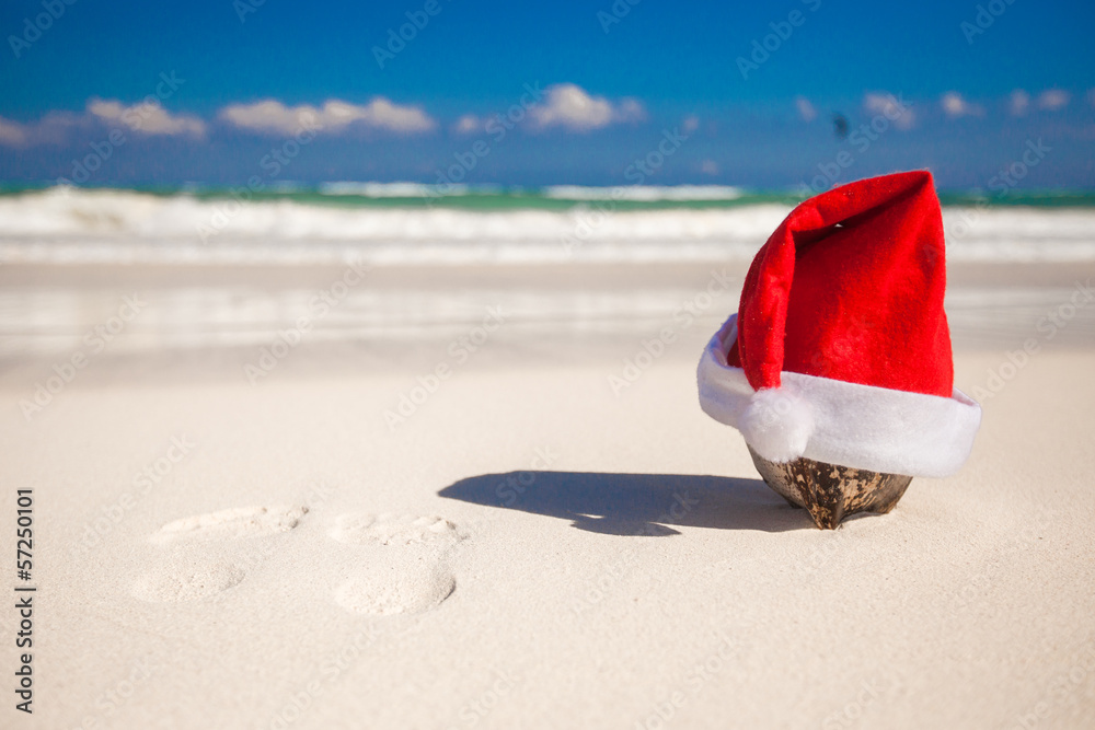 Santa Claus hat at coconut on a white sandy beach Santa Claus hat at coconut on a white sandy beach