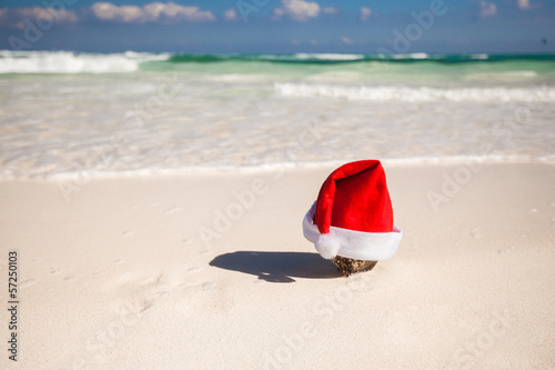 Christmas hat at coconut on a white sandy beach