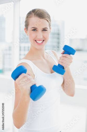 Sporty smiling woman exercising with dumbbells