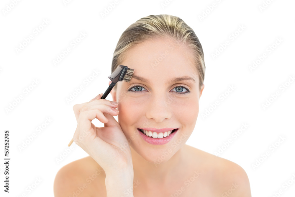 Happy fresh blonde woman brushing her eyebrows Happy fresh blonde woman brushing her eyebrows