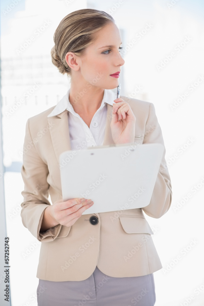 Pensive blonde businesswoman holding clipboard Pensive blonde businesswoman holding clipboard