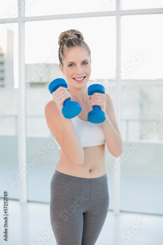 Cheerful athletic blonde exercising with dumbbells