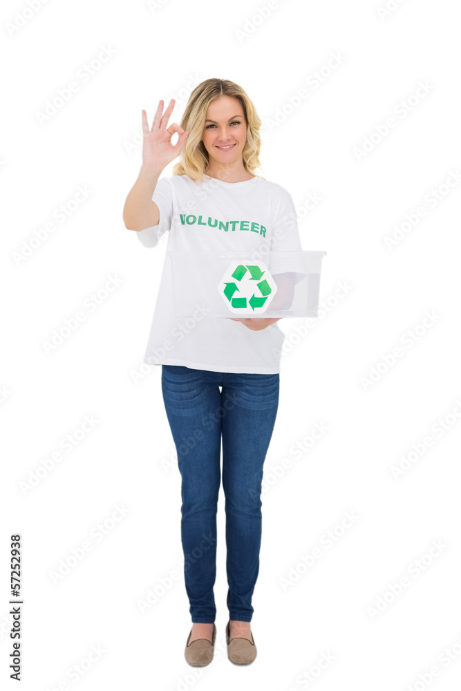 Smiling blonde volunteer holding recycling box making okay gestu Smiling blonde volunteer holding recycling box making okay gestu