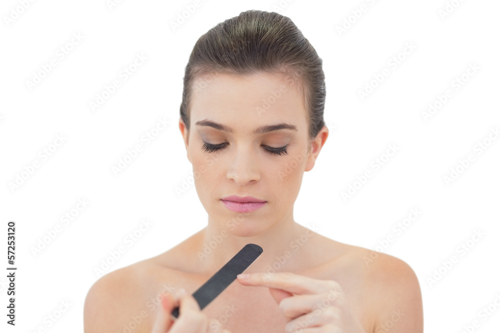 Pensive natural brown haired model filing her nails Pensive natural brown haired model filing her nails
