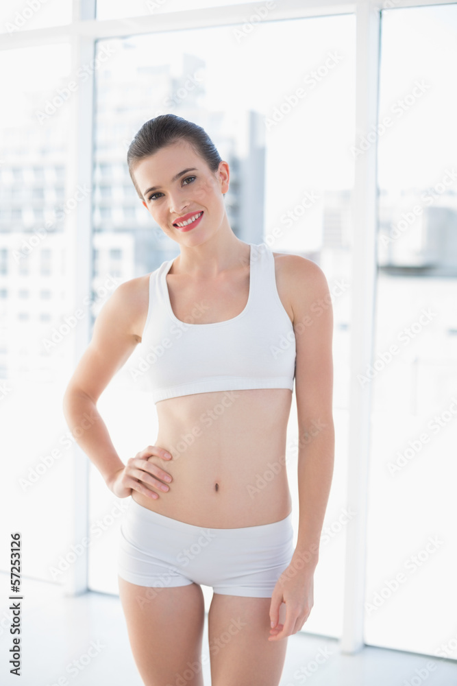 Amused fit brown haired model in sportswear posing with a hand o