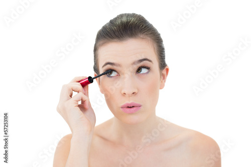 Concentrated natural brown haired model applying mascara