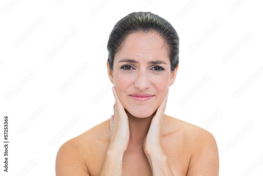 Troubled bare brunette touching her neck with both hands Troubled bare brunette touching her neck with both hands