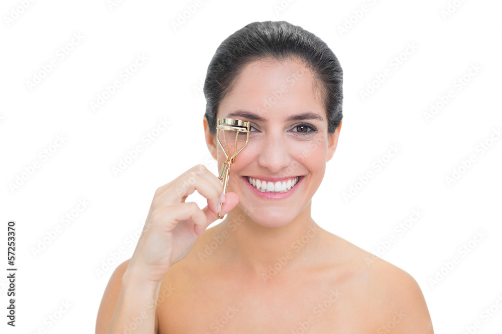 Smiling bare brunette using eyelash curler Smiling bare brunette using eyelash curler
