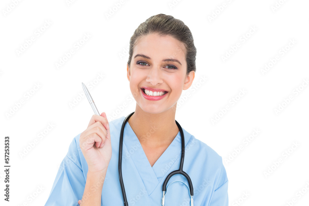 Pleased brown haired nurse in blue scrubs holding a pen Pleased brown haired nurse in blue scrubs holding a pen