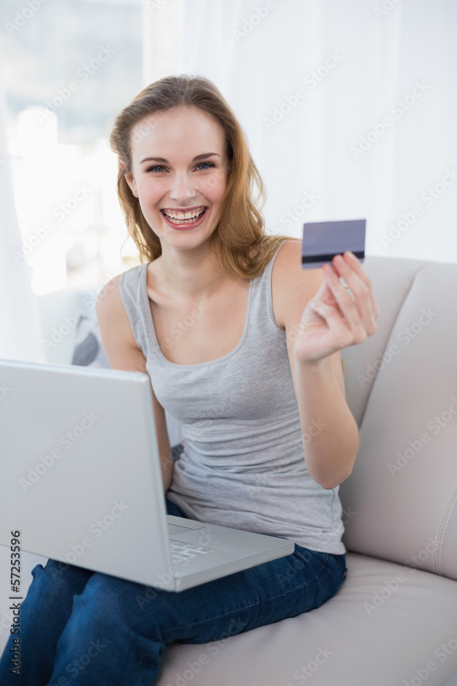 Laughing young woman sitting on couch using laptop for online sh Laughing young woman sitting on couch using laptop for online sh
