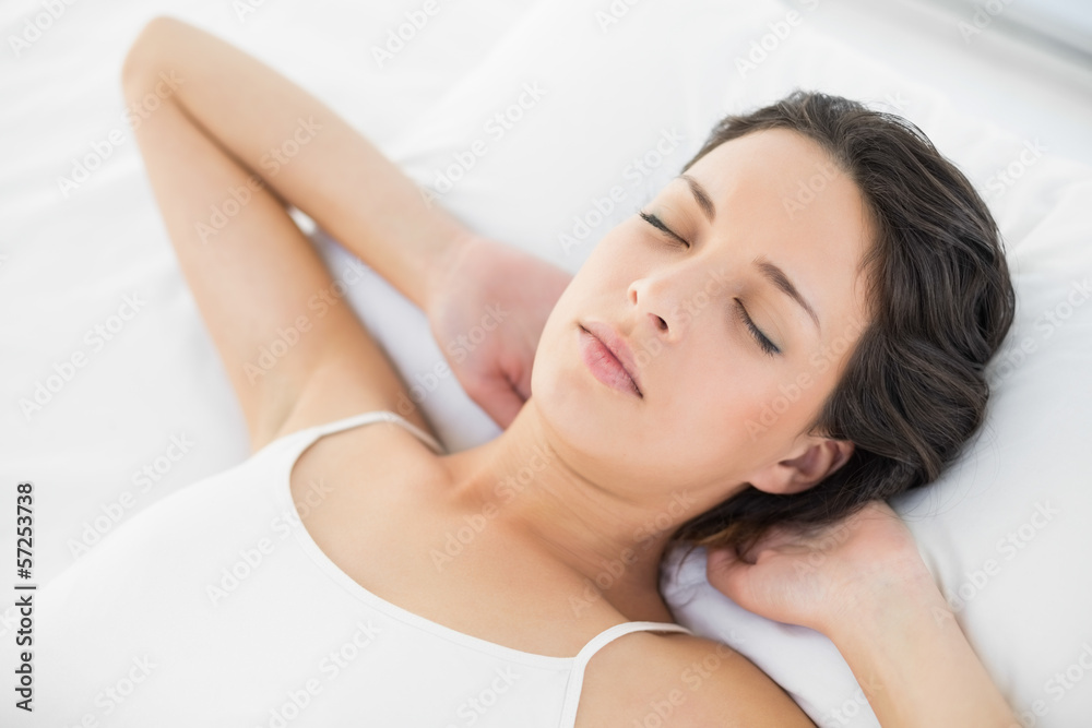 Beautiful casual brunette in white pajamas resting on her bed Beautiful casual brunette in white pajamas resting on her bed