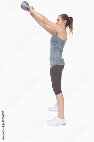 Profile view of ponytailed woman training with a kettle bell