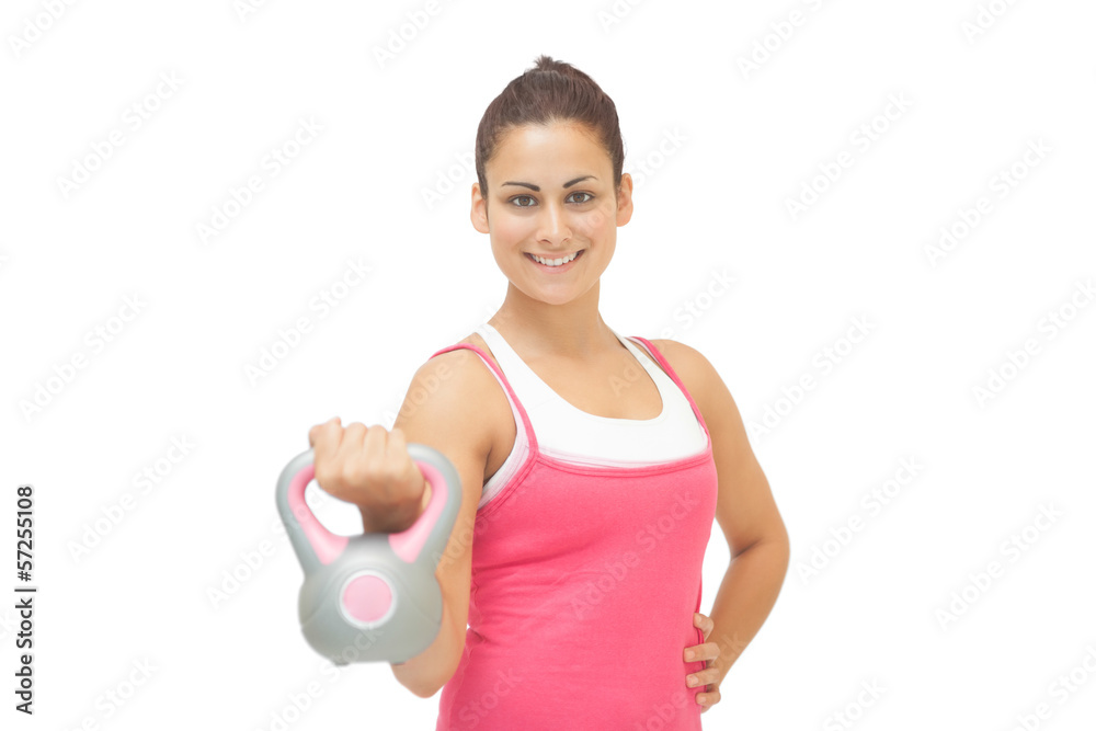 Cheerful sporty brunette holding grey and pink kettlebell Cheerful sporty brunette holding grey and pink kettlebell