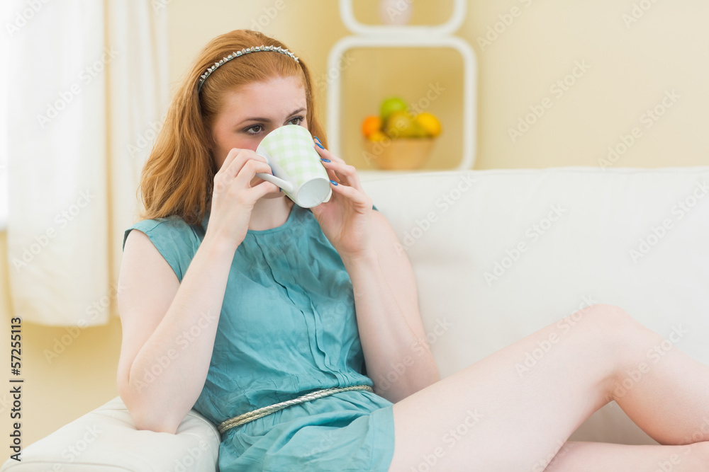 Relaxed redhead sitting on the couch and drinking coffee Relaxed redhead sitting on the couch and drinking coffee