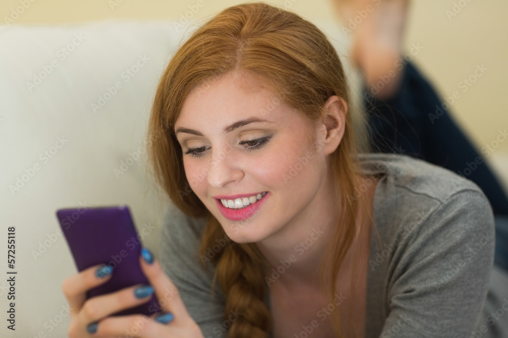 Pretty redhead lying on the sofa sending a text