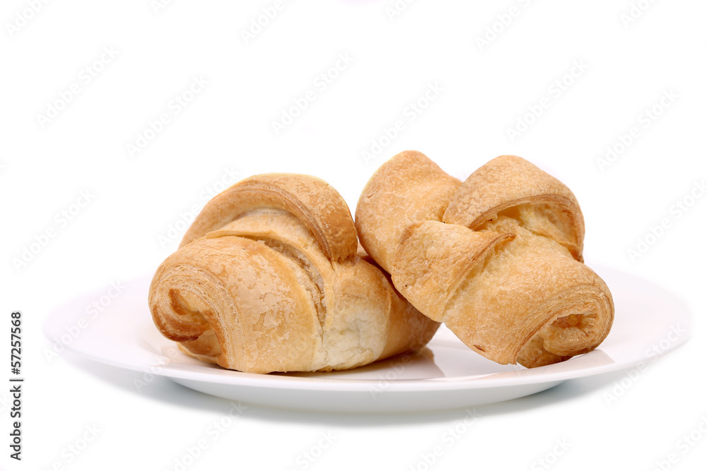 Fresh croissants on white plate.