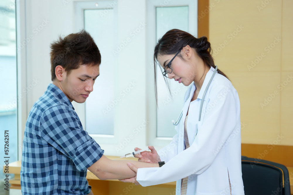 Fototapeta premium Young woman doctor giving male patient injection