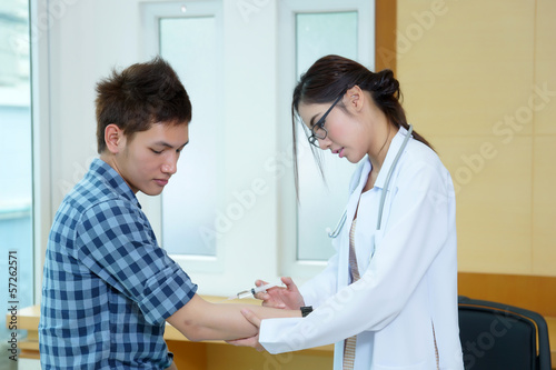 Young woman doctor giving male patient injection