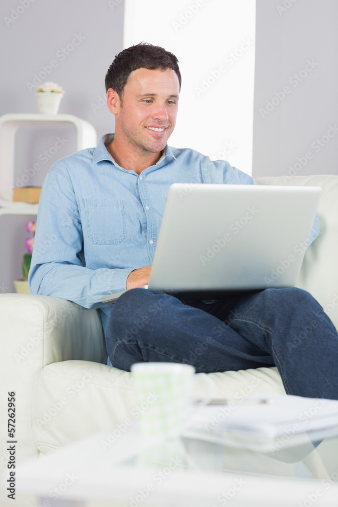Laughing casual man sitting on couch using laptop Laughing casual man sitting on couch using laptop