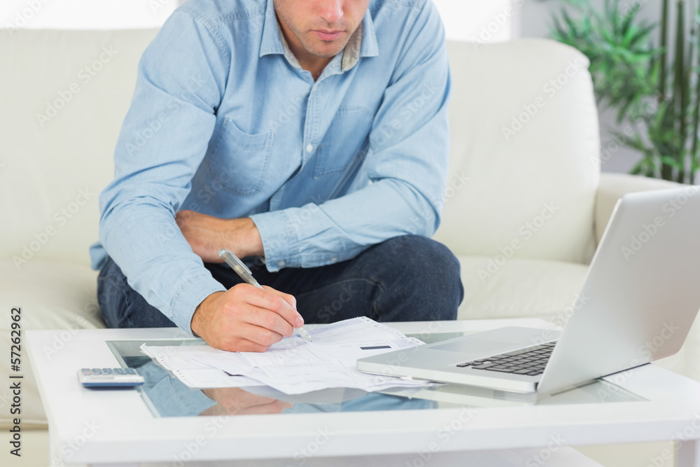 Close up of man writing on sheets paying bills Close up of man writing on sheets paying bills