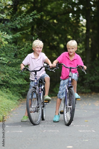 Two teenagers boys, twin brothers are cycling in the park 