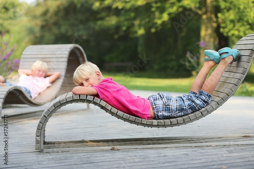Two boys chilling out at wooden ergonomic chairs in park photo
