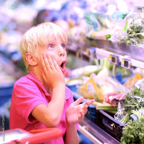 Cute teenager boy at vegetables department in supermarket