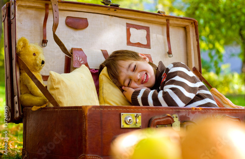 Little boy sleeps in a large suitcase in the autumn park