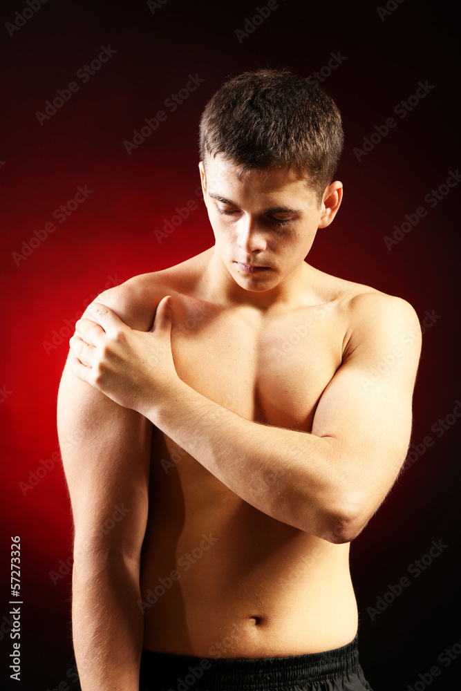 Young man with shoulder pain, on red background