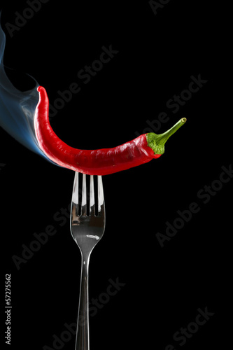 Red hot chili pepper on fork, isolated on black © Africa Studio