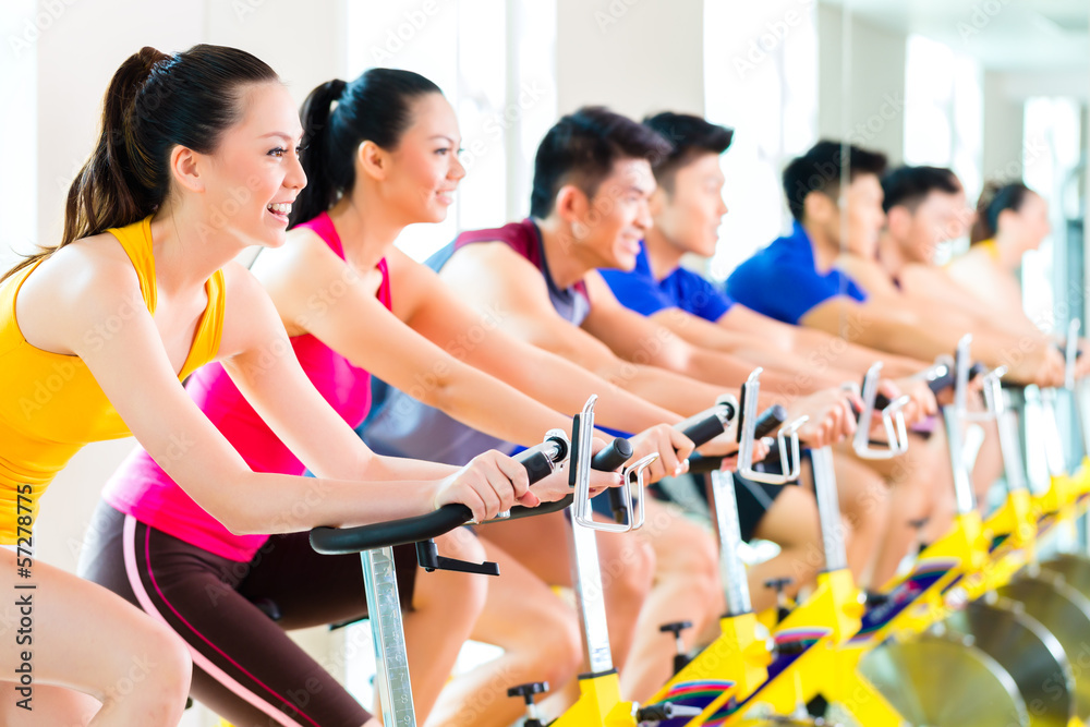 Asian people in spinning bike training at fitness gym Asian people in spinning bike training at fitness gym