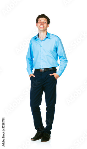 Happy young businessman standing with his hands in pockets on wh