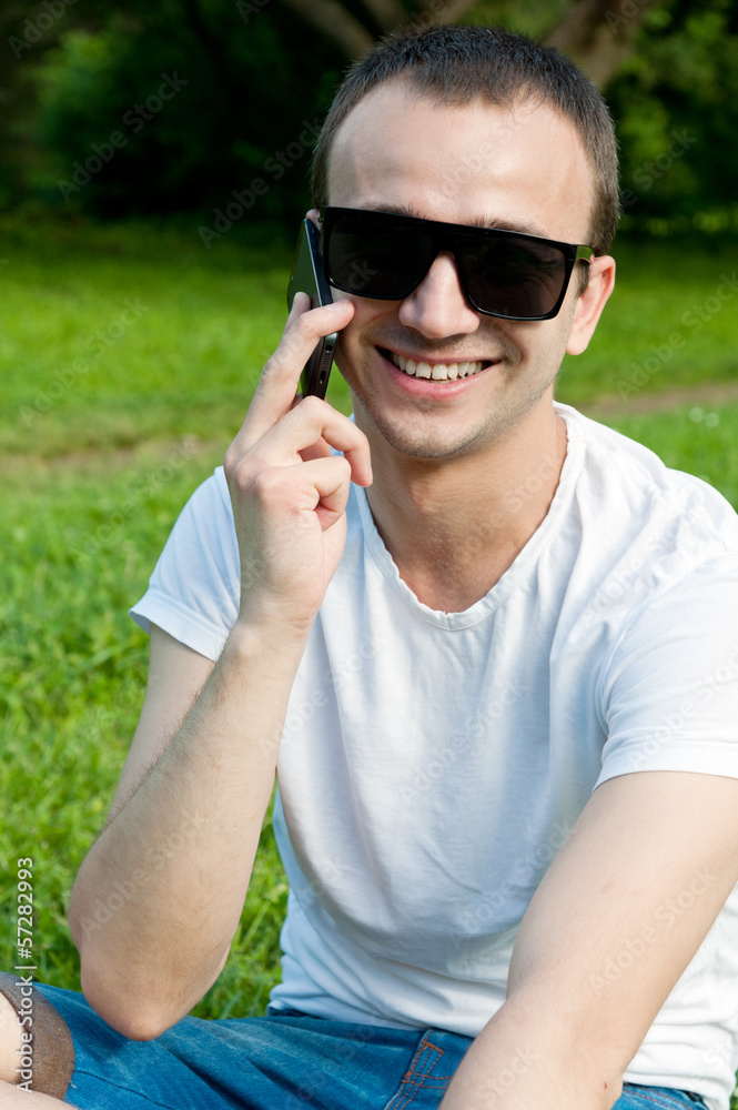 Young man speaks on the phone on the grass Young man speaks on the phone on the grass
