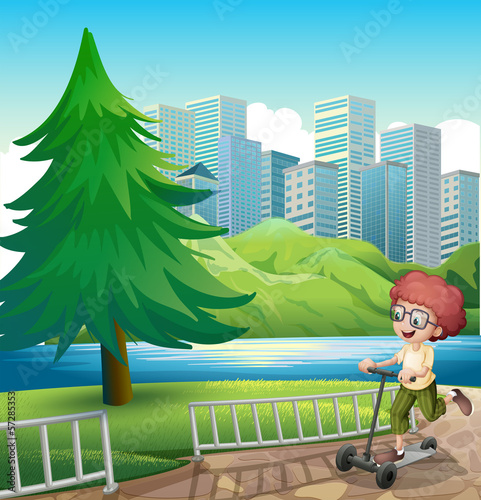 A happy young boy playing with his scooter near the river