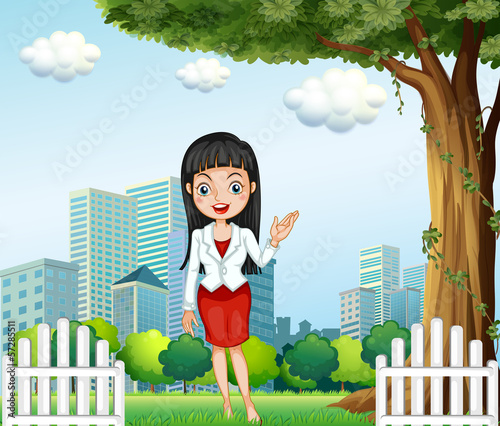A pretty lady standing near the tree across the buildings