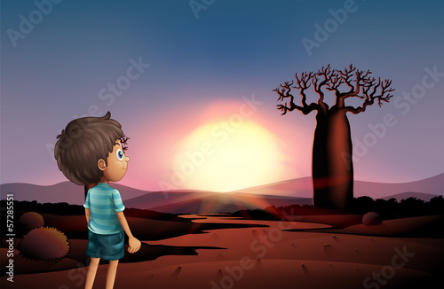 A boy at the desert watching the sunset