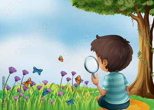 A young boy holding a magnifying lens at the garden in the hillt