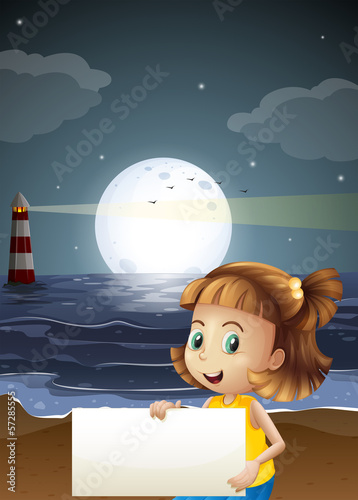 A cute little girl holding an empty signboard at the beach