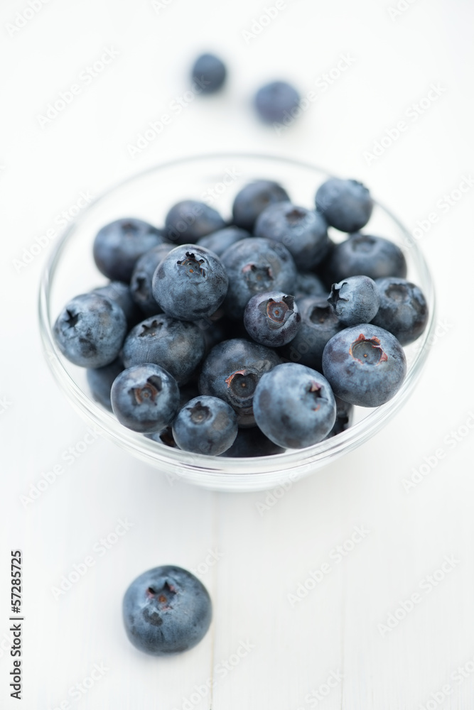 Glass bowl with blueberries on white wooden board, vertical shot Glass bowl with blueberries on white wooden board, vertical shot