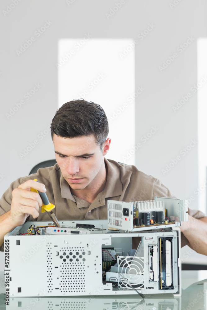 Obraz premium Handsome serious computer engineer repairing open computer