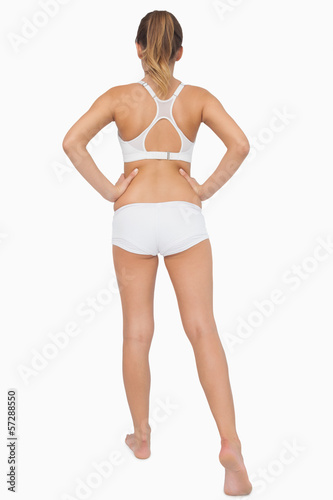 Rear view of ponytailed woman stretching her legs