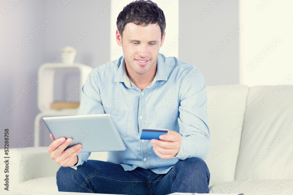 Smiling casual man using tablet and credit card Smiling casual man using tablet and credit card