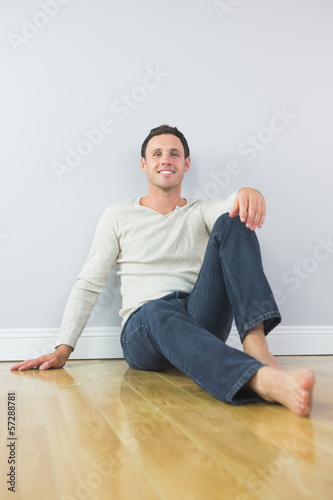 Casual smiling man leaning against wall looking at camera