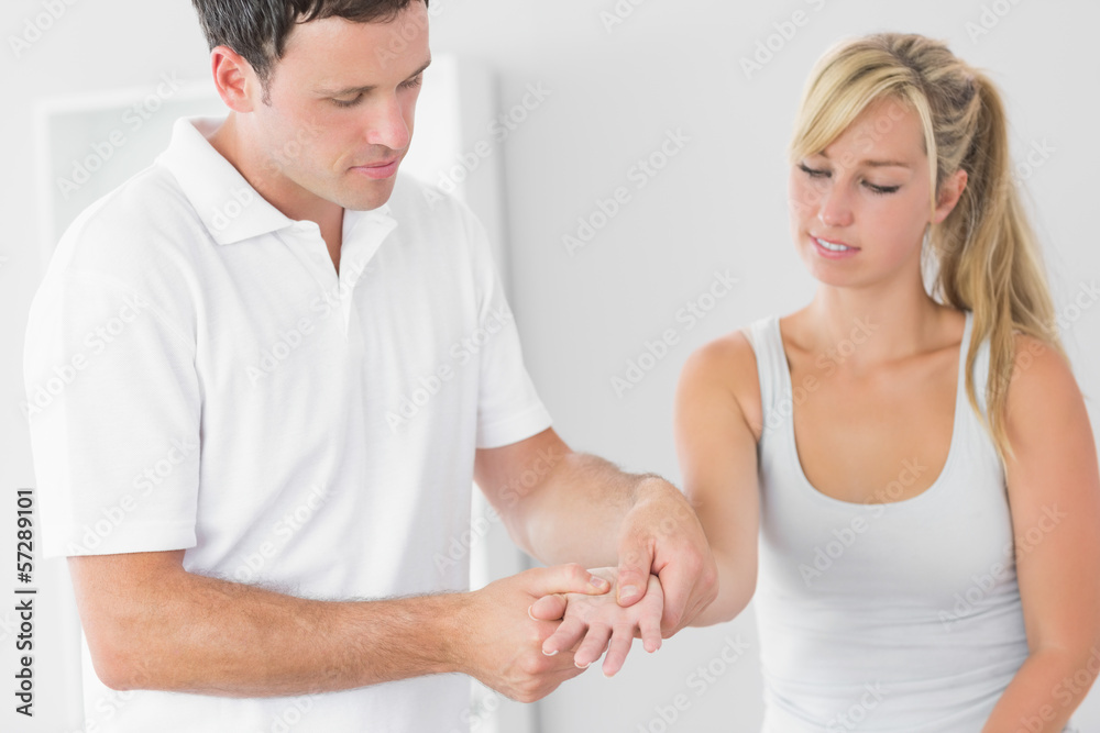 Obraz premium Pleased physiotherapist examining patients hand