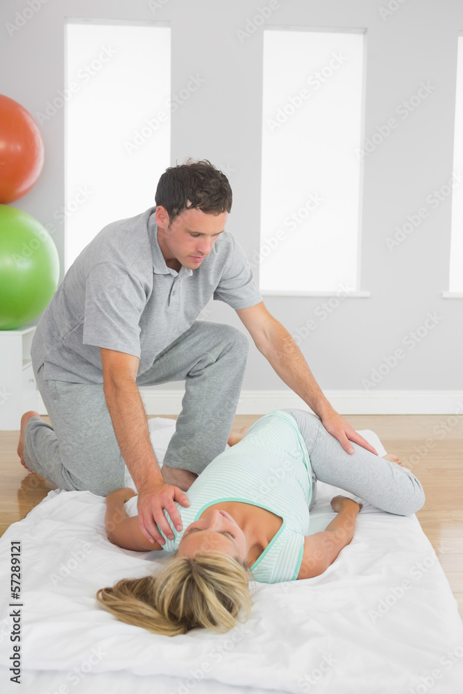 Fototapeta premium Physiotherapist examining patients hips on a mat on the floor